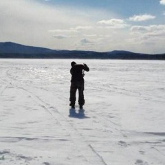 a solitary man on a bucket, fishing through eighteen inches of ice in a lake that's constantly tu...