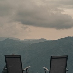 Two Chairs In The Middle Of A Field In Between Two Mountains