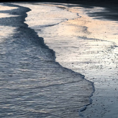 Ocean Waves onto sandy beach at dusk